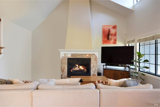 living room with a fireplace, plenty of natural light, and high vaulted ceiling