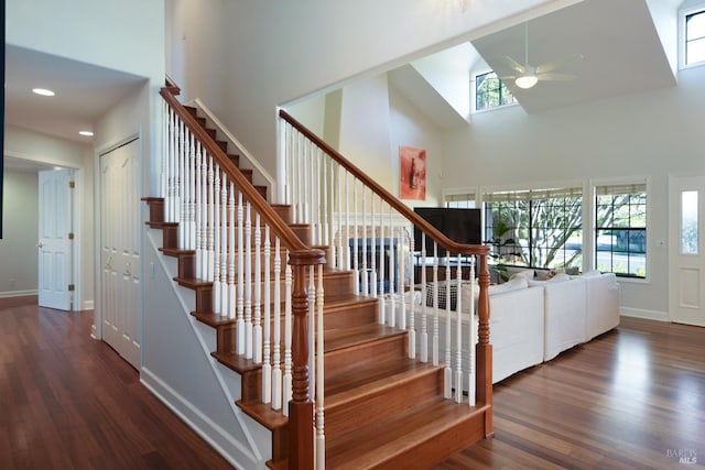 stairway featuring a towering ceiling, hardwood / wood-style flooring, and ceiling fan