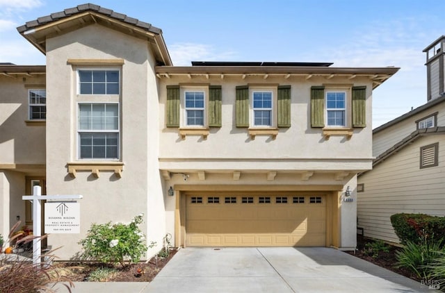 view of front of home featuring concrete driveway, an attached garage, and stucco siding