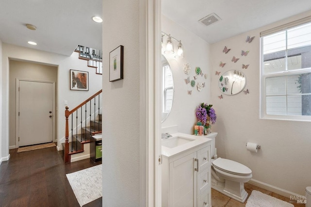 bathroom featuring visible vents, vanity, wood finished floors, toilet, and baseboards