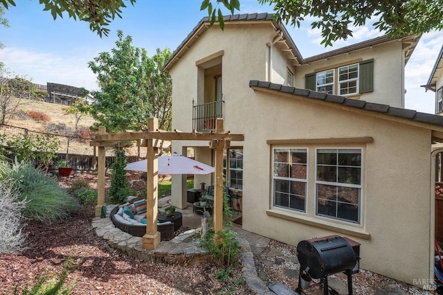 rear view of house with stucco siding, fence, a balcony, and a patio