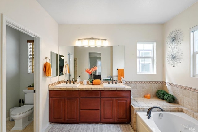 bathroom with a sink, a garden tub, toilet, and double vanity