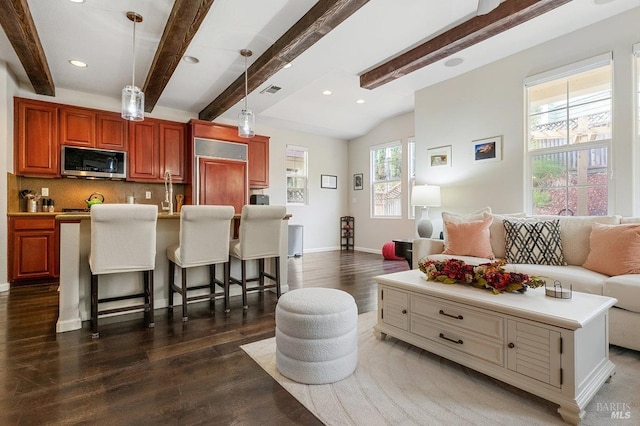 living room featuring beam ceiling, dark hardwood / wood-style floors, and plenty of natural light