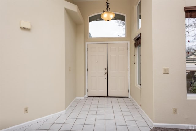 entryway featuring light tile patterned flooring and a towering ceiling