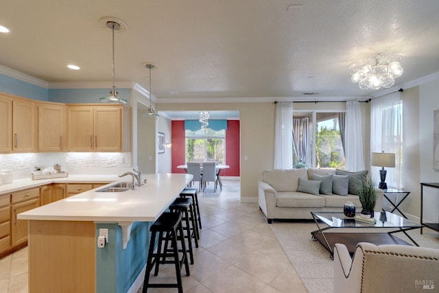 kitchen with ornamental molding, sink, light brown cabinets, decorative light fixtures, and a notable chandelier