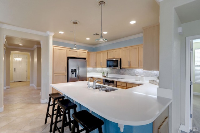 kitchen featuring appliances with stainless steel finishes, a breakfast bar, sink, light brown cabinets, and hanging light fixtures