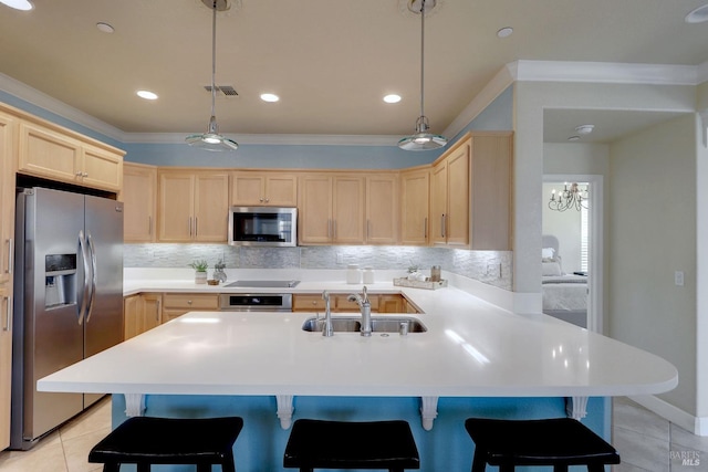 kitchen featuring a breakfast bar, hanging light fixtures, sink, and appliances with stainless steel finishes