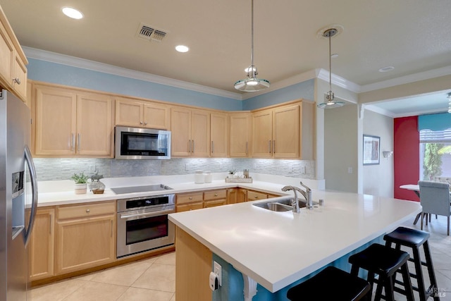 kitchen with light brown cabinets, sink, decorative light fixtures, a breakfast bar area, and appliances with stainless steel finishes