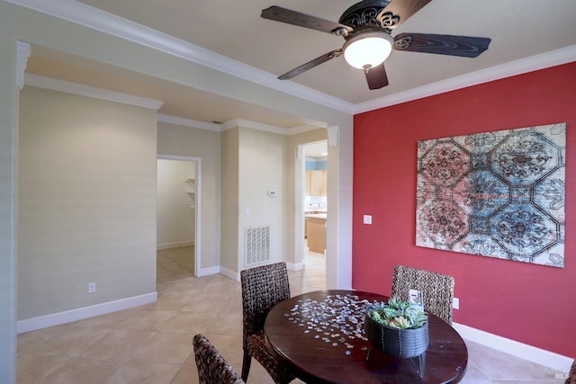 tiled dining area with ceiling fan and crown molding