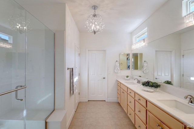 bathroom with tile patterned floors, a notable chandelier, a shower with door, and vanity