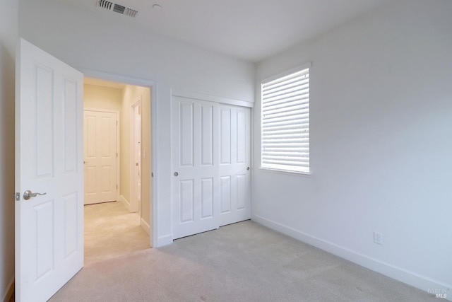 unfurnished bedroom with light colored carpet and a closet