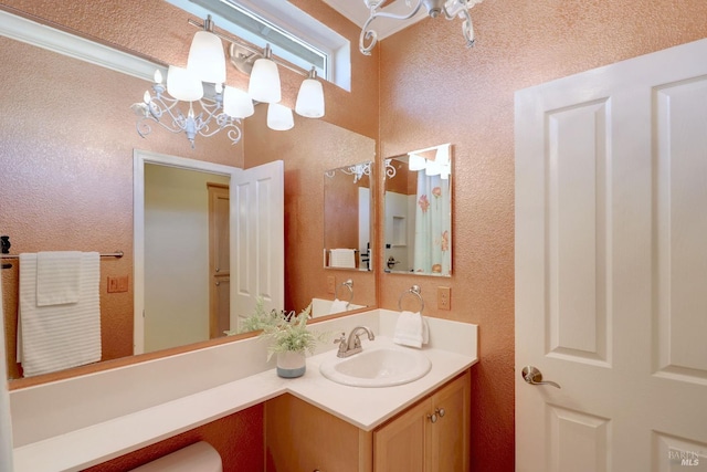 bathroom with vanity, crown molding, and an inviting chandelier