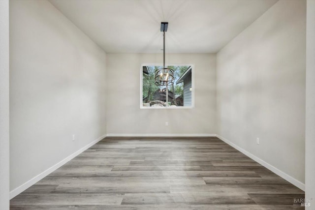 unfurnished dining area with wood-type flooring and a notable chandelier