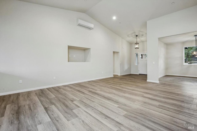 unfurnished living room featuring vaulted ceiling, light hardwood / wood-style floors, and an AC wall unit