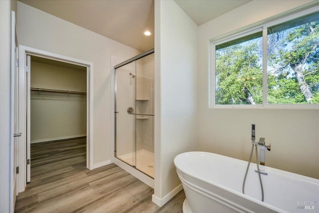 bathroom with hardwood / wood-style flooring and shower with separate bathtub