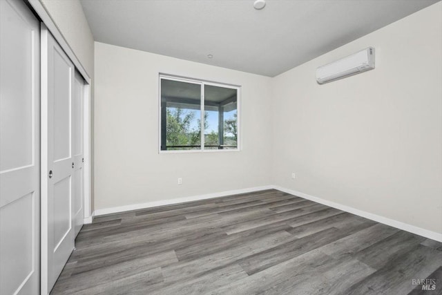 unfurnished bedroom with dark hardwood / wood-style floors, a wall mounted air conditioner, and a closet