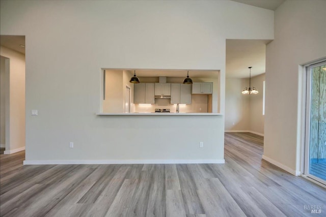 unfurnished living room with a chandelier and light hardwood / wood-style floors