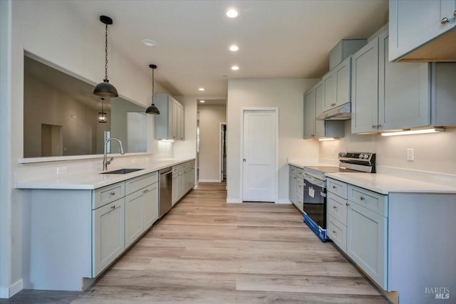 kitchen featuring stainless steel appliances, decorative light fixtures, light hardwood / wood-style floors, and sink