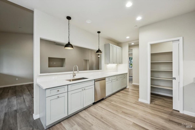 kitchen with decorative light fixtures, dishwasher, sink, and light hardwood / wood-style flooring