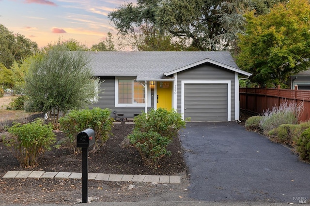 view of front of property featuring aphalt driveway, roof with shingles, fence, and an attached garage