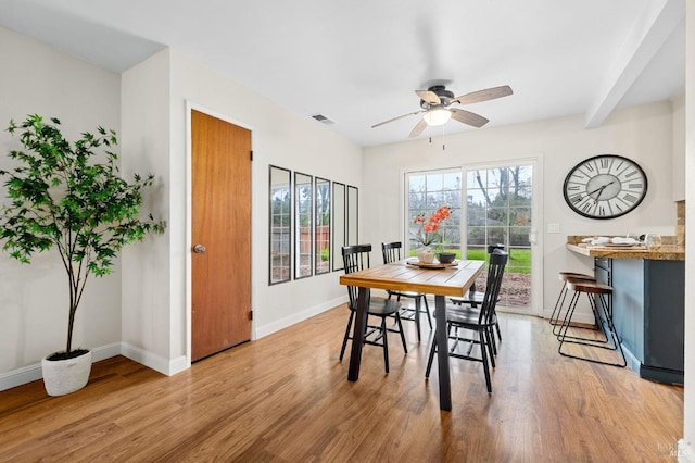 dining room featuring a ceiling fan, light wood-type flooring, visible vents, and baseboards