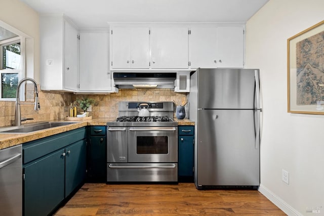 kitchen featuring extractor fan, a sink, white cabinetry, light countertops, and appliances with stainless steel finishes