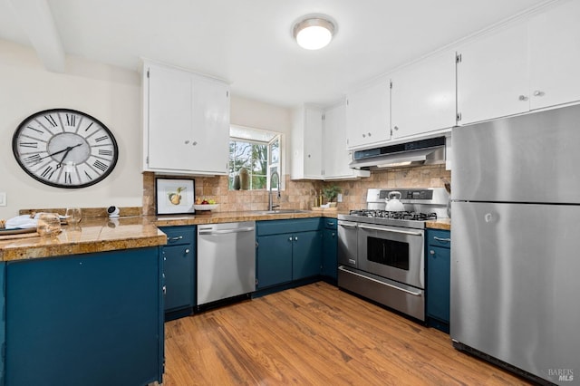 kitchen featuring blue cabinetry, appliances with stainless steel finishes, white cabinetry, a sink, and under cabinet range hood