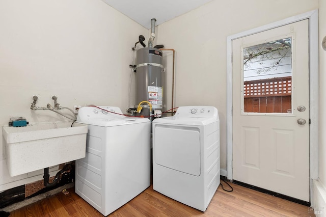 laundry area featuring laundry area, a sink, light wood-style floors, water heater, and washing machine and clothes dryer