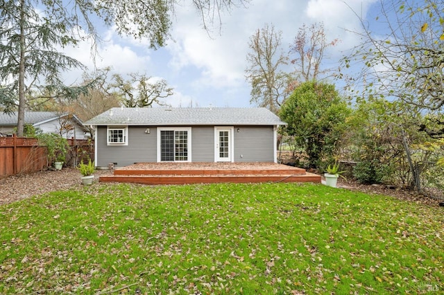 rear view of house featuring fence and a lawn