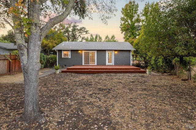 back of property at dusk featuring fence and a deck