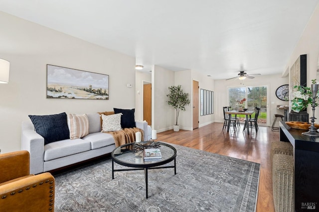 living room featuring ceiling fan, baseboards, and wood finished floors