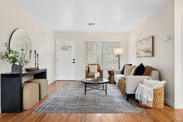 living room featuring wood finished floors, visible vents, and baseboards