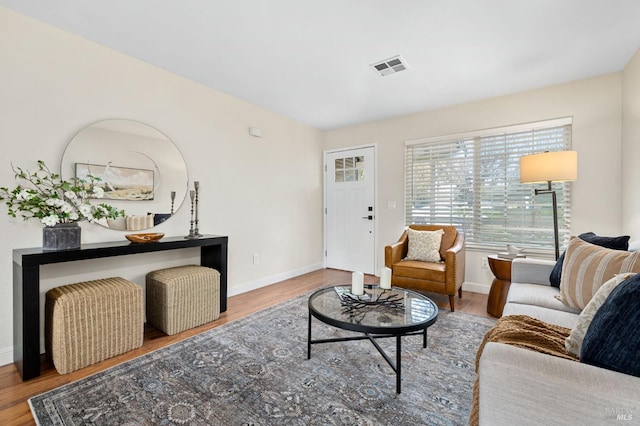 living room featuring visible vents, baseboards, and wood finished floors