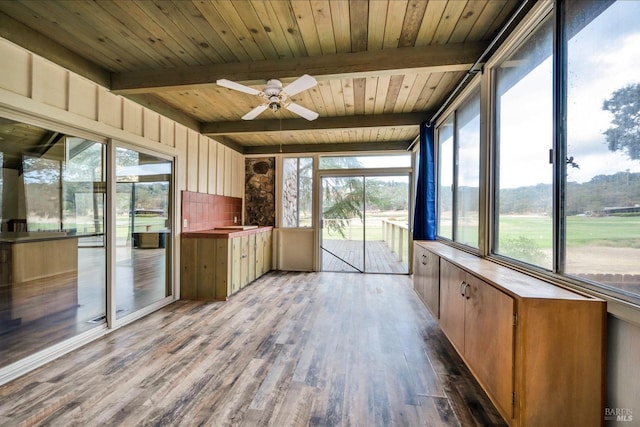 unfurnished sunroom with beam ceiling, ceiling fan, and a healthy amount of sunlight