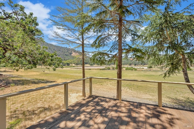 wooden deck with a mountain view and a lawn