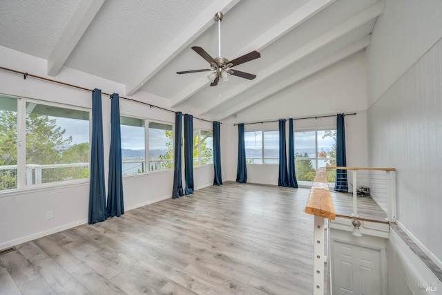 unfurnished room with vaulted ceiling with beams, ceiling fan, light hardwood / wood-style floors, and a textured ceiling