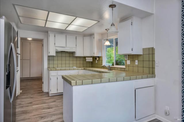 kitchen featuring tasteful backsplash, pendant lighting, tile countertops, stainless steel fridge with ice dispenser, and white cabinetry