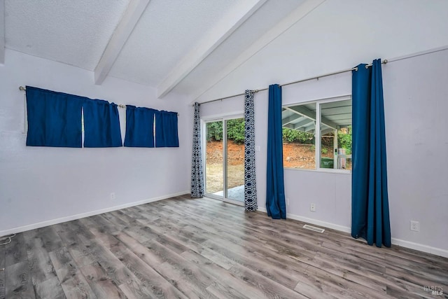 spare room featuring beamed ceiling, wood-type flooring, a textured ceiling, and high vaulted ceiling