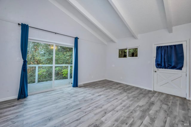 unfurnished room with vaulted ceiling with beams, plenty of natural light, and light wood-type flooring