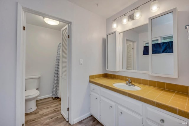 bathroom with wood-type flooring, vanity, and toilet