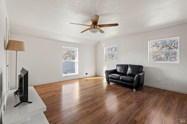 living area featuring ceiling fan, dark wood-type flooring, and a textured ceiling