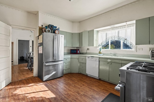 kitchen featuring appliances with stainless steel finishes, dark hardwood / wood-style flooring, green cabinets, and sink