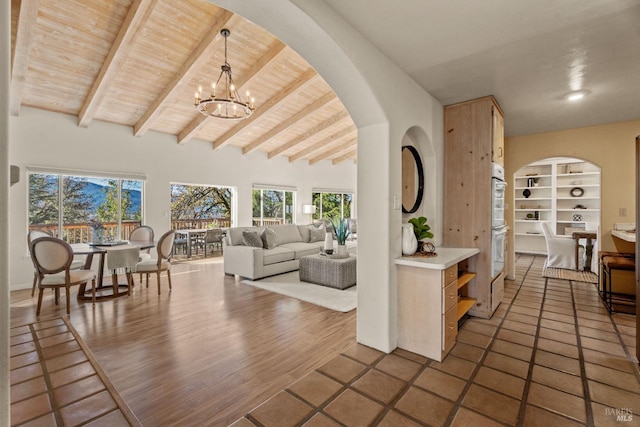 living room featuring built in features, dark hardwood / wood-style floors, lofted ceiling with beams, wooden ceiling, and a chandelier