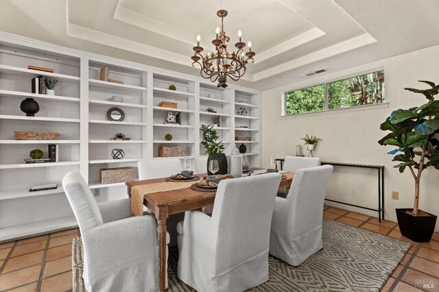 dining space featuring a raised ceiling, tile patterned flooring, and a notable chandelier