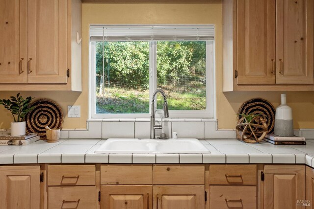 kitchen with tile countertops, sink, and light brown cabinets