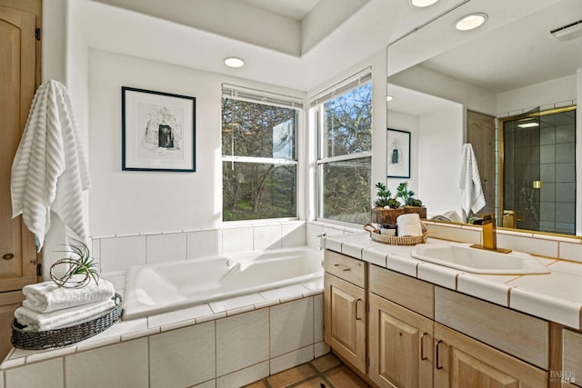 bathroom featuring vanity, tile patterned flooring, and tiled bath