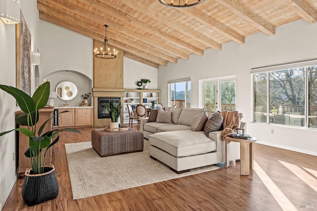 living room with wood-type flooring, high vaulted ceiling, wooden ceiling, a large fireplace, and a notable chandelier