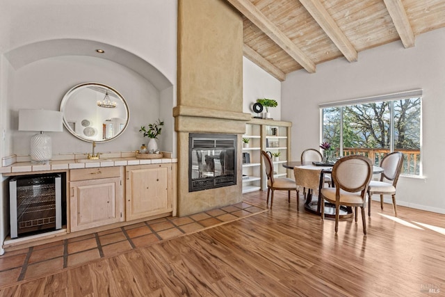 interior space featuring tile countertops, wooden ceiling, beverage cooler, and light wood-type flooring