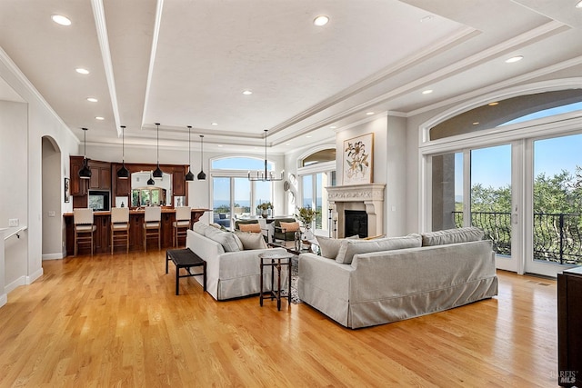 living room featuring ornamental molding, light hardwood / wood-style flooring, and a tray ceiling