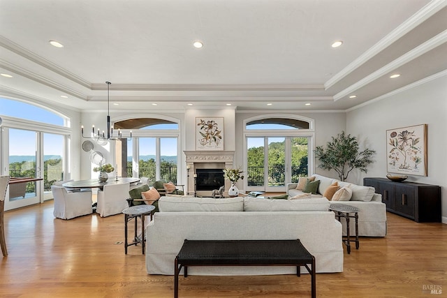 living room featuring light wood-type flooring, ornamental molding, and a tray ceiling